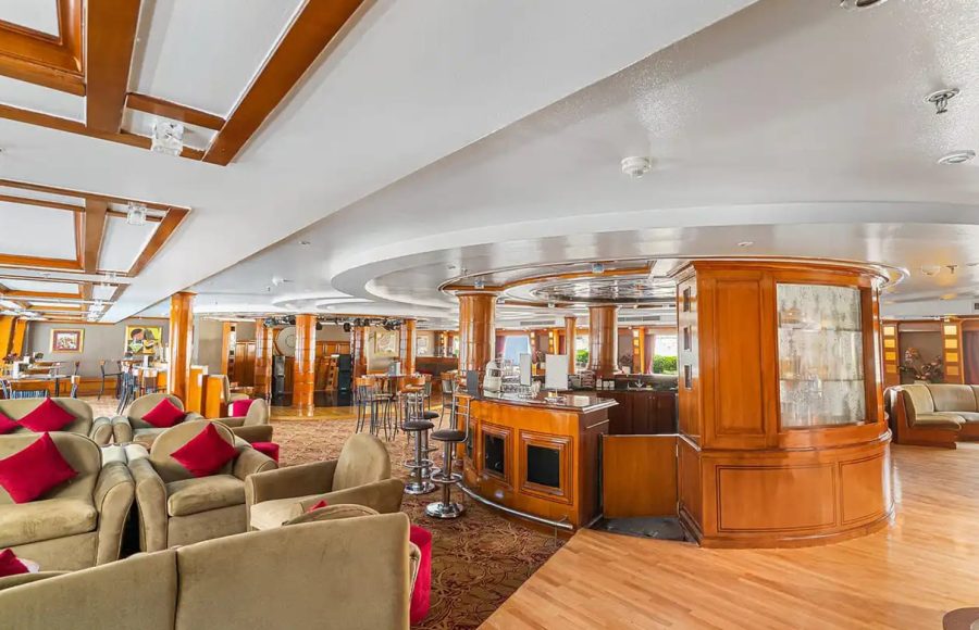 Cruise ship lobby with mezzanine, gift shop displays, and a massage treatment sign.