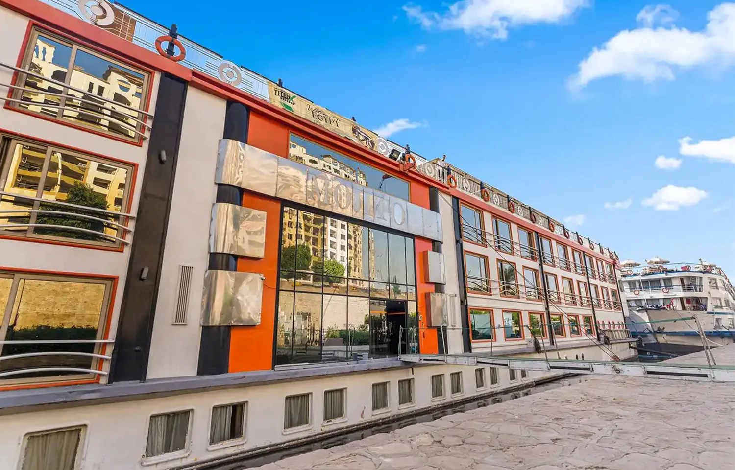 Exterior of Nile cruise ship docked, featuring orange and white facade.