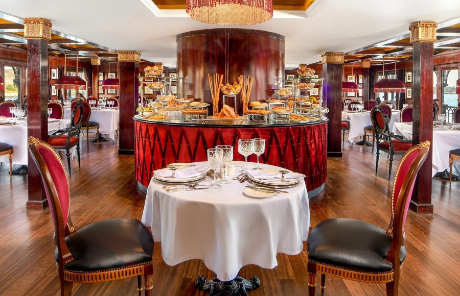 Step inside the elegant dining room of the SS Misr Nile Cruise, featuring a grand buffet and beautifully set tables for an unforgettable culinary experience.