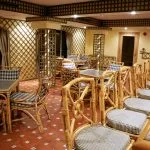 An indoor lounge area with bamboo furniture, checkered cushions, and a granite-topped bar.