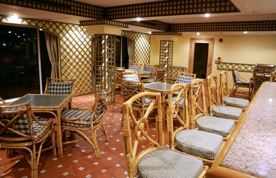An indoor lounge area with bamboo furniture, checkered cushions, and a granite-topped bar.