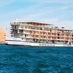 The Mövenpick Prince Abbas cruise ship sailing on deep blue water under a clear sky.