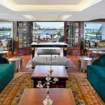 The opulent Lounge on the Mövenpick SS Misr cruise with plush seating and doors opening to the panoramic views of the Nile.