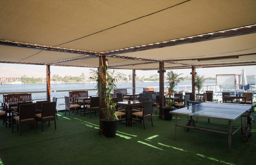 Sun deck area with shaded seating and a ping-pong table on the Commodore Nile Cruise boat.