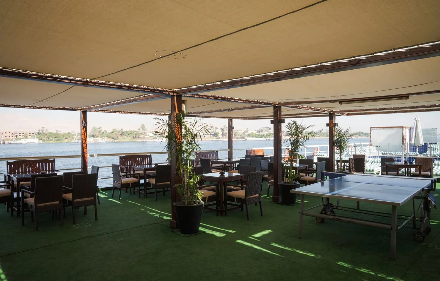 Sun deck area with shaded seating and a ping-pong table on the Commodore Nile Cruise boat.