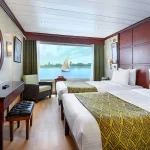 Twin-bed cabin on a Nile cruise ship with a mirror and desk, ideal for a 10 day Egypt Itinerary beach and culture.