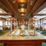 Buffet area in a cruise ship dining room with a granite food counter and displays of appetizers and salads.