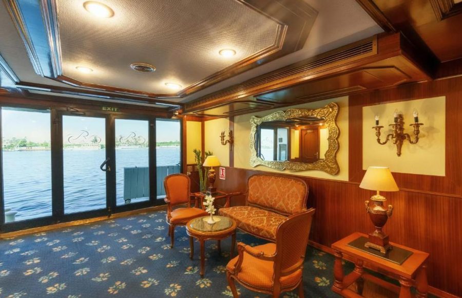 Curved bar area on a cruise ship with brown leather bar stools, a polished granite counter, and shelves of liquor bottles.