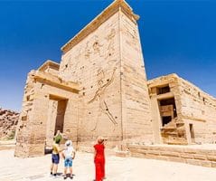 A family views the ancient Philae Temple, adorned with carvings, as a stop on their Standard Nile Cruise trip.