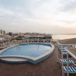Oval-shaped outdoor swimming pool on a wooden cruise deck by the railing.
