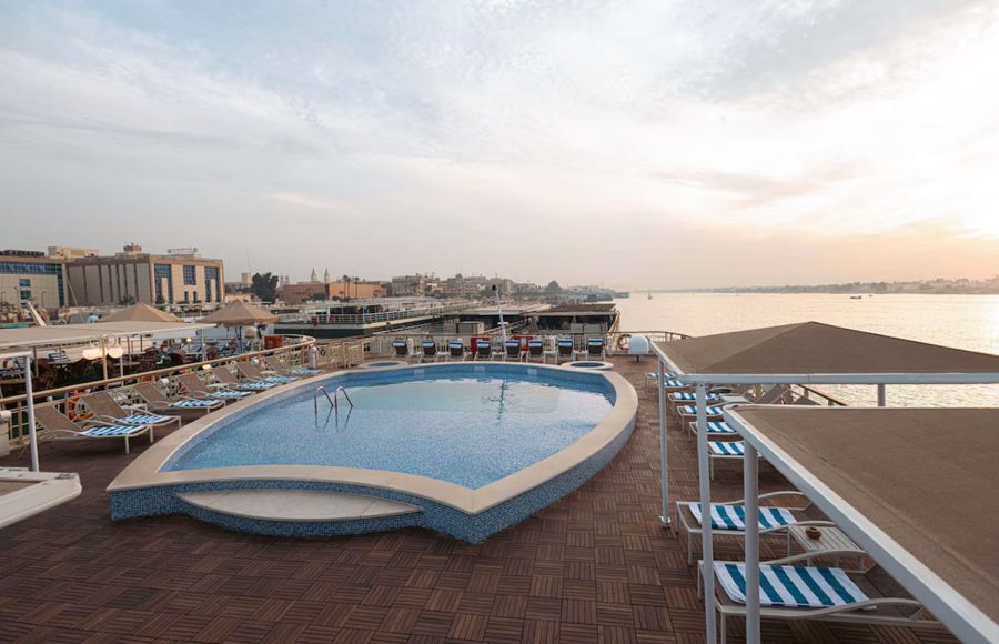 Oval-shaped outdoor swimming pool on a wooden cruise deck by the railing.