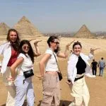 Happy group of friends posing playfully in front of the Giza plateau during their Cairo pyramids and museum excursion