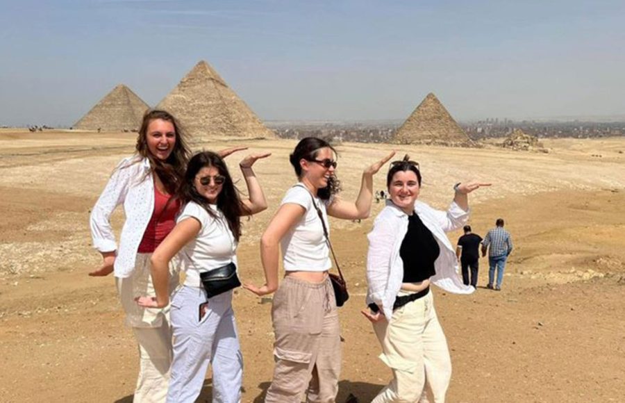 Happy group of friends posing playfully in front of the Giza plateau during their Cairo pyramids and museum excursion