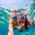Two people wearing snorkeling masks and a life vest in clear turquoise water in their 6 days Cairo and Hurghada Holiday.