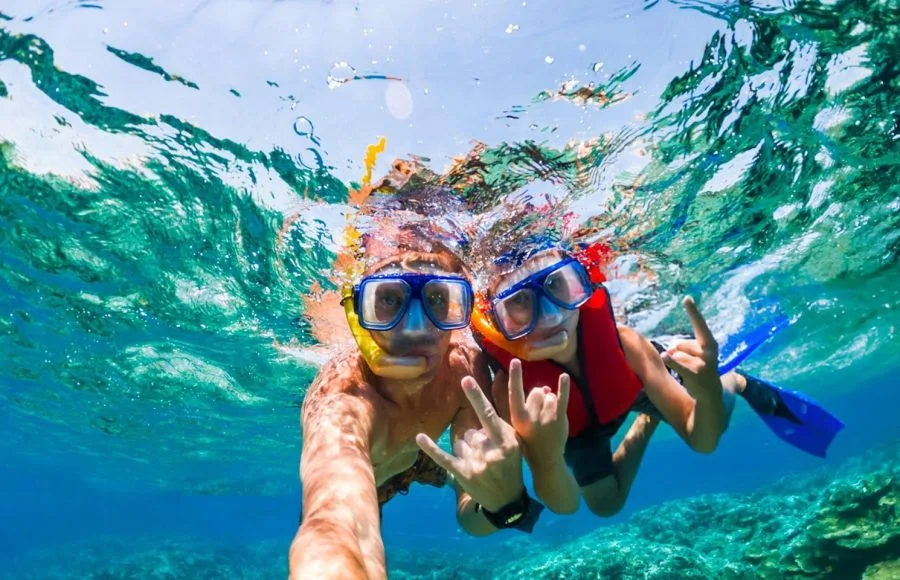 Two people wearing snorkeling masks and a life vest in clear turquoise water in their 6 days Cairo and Hurghada Holiday.