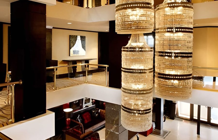 A multi-story ship atrium featuring a grand crystal chandelier and golden railings.