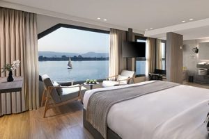 An elegant cabin on a luxury Nile River cruise ship with a large window overlooking the Nile and a traditional felucca. Luxury Nile River cruise.